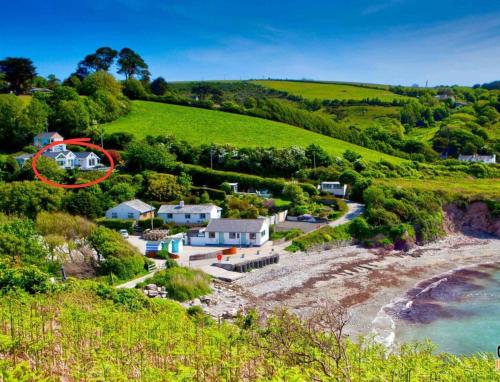 an aerial view of a house on a hill next to the ocean at Beach Front House with Stunning Sea Views and Free Use of a Local Indoor Pool in Talland