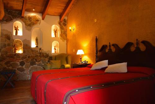 a bedroom with a red bed with a stone wall at Hotel Candelaria Antigua in Antigua Guatemala