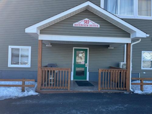 un edificio con un porche delantero con una puerta verde en Riverview Suites, en Clarenville
