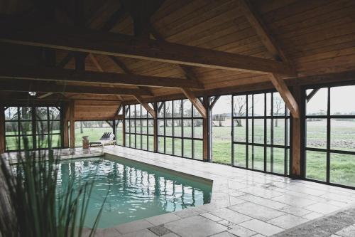 - une grande piscine dans un pavillon avec fenêtres dans l'établissement Magnifique maison au coeur du Perche avec piscine chauffée, sauna et hammam, à Grande Courbetière