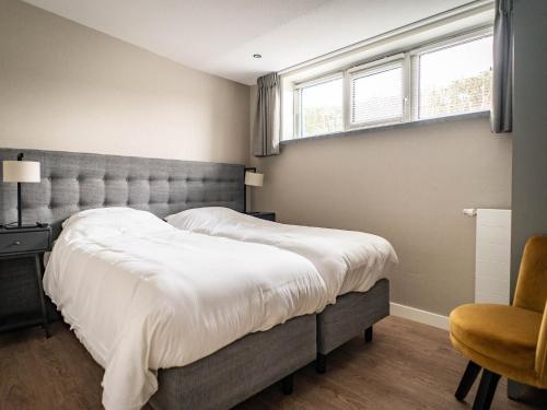 a bedroom with a large bed and a chair at Pet-Friendly Texel Escape in De Cocksdorp