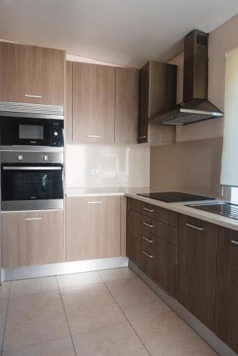 a kitchen with wooden cabinets and a stove top oven at Flor do Mar House in Ponta Delgada