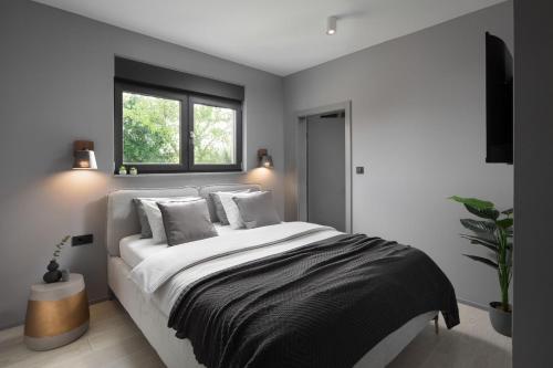 a bedroom with a large white bed with a window at Villa Anthea and Paola in Nedeščina