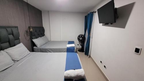 a small room with two beds and a flat screen tv at ANDALIVING NIQUIA Apartaestudio in Bello