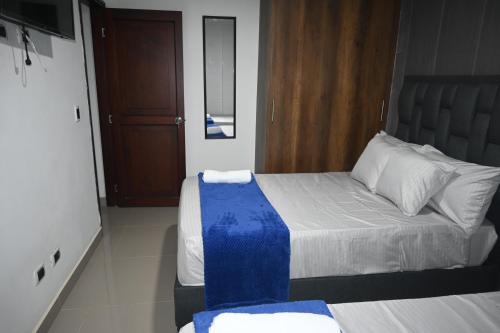 a bedroom with a bed with blue and white sheets at ANDALIVING NIQUIA Apartaestudio in Bello