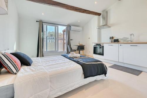 - une chambre blanche avec un grand lit et une cuisine dans l'établissement charmant studio climatisé pres de notre dame de la garde, à Marseille