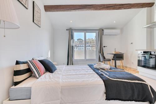 une chambre blanche avec un grand lit et une fenêtre dans l'établissement charmant studio climatisé pres de notre dame de la garde, à Marseille
