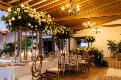 a dining room with tables and chairs with flowers at Hotel Hacienda El Novillero in Fusagasuga