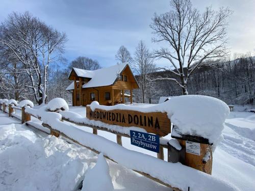 a sign in the snow in front of a log cabin at Niedźwiedzia Dolina in Przybyszów