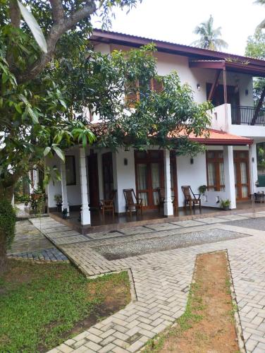 a house with chairs and a patio in front of it at Villa Muthuwin in Panadura