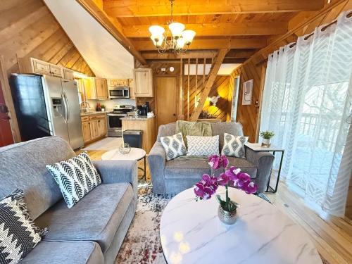 a living room with couches and a table with flowers on it at Plentiful Porches - Hot Tub - King Bed - Views in Banner Elk