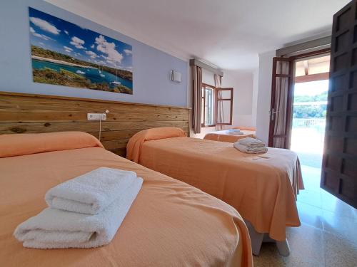 a bedroom with two beds with towels on them at Hostal Playa in Cala Santanyi