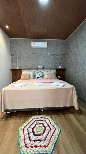 a bedroom with a large bed with a rug on the floor at POUSADA IRMAOS ATINS in Atins