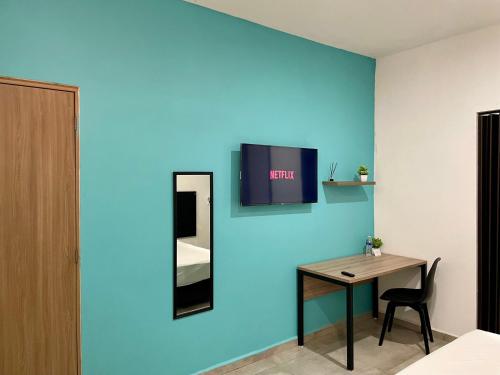 a room with a table and a tv on a blue wall at Estudios Rios Habitación in Zamora de Hidalgo