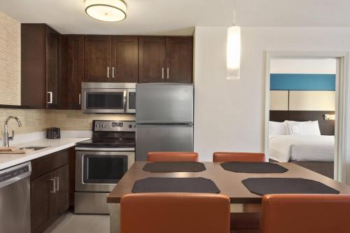a kitchen with a table with chairs and a bed at Residence Inn by Marriott St. Paul Woodbury in Woodbury