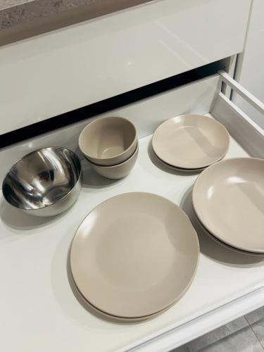 four white plates and bowls on a kitchen counter at studio apartment in Vilnius