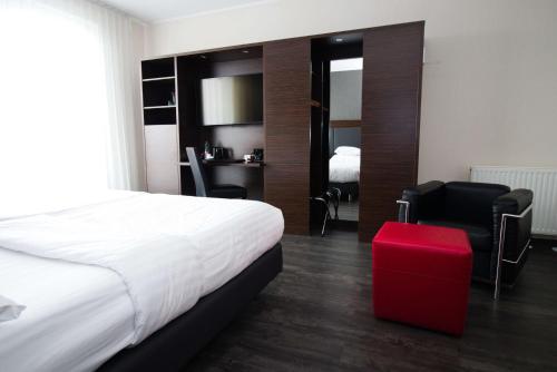 een hotelkamer met een bed en een rode kruk bij Best Western Plus Plaza Hotel Graz in Graz
