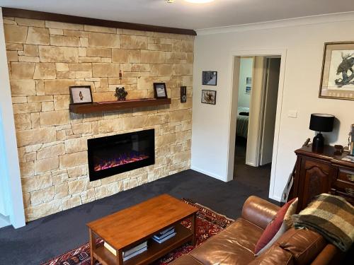 a living room with a stone wall with a fireplace at Ski, Mtn Bike or Hike from the heart of Thredbo in Thredbo