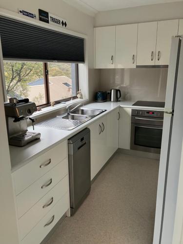 a kitchen with white cabinets and a sink and a window at Ski, Mtn Bike or Hike from the heart of Thredbo in Thredbo