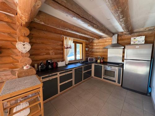 - une cuisine dans une cabane en rondins avec un réfrigérateur dans l'établissement Chalet les SORBIERS, en rondins, classé 4****étoiles, à Bolquère-Pyrénées 2000