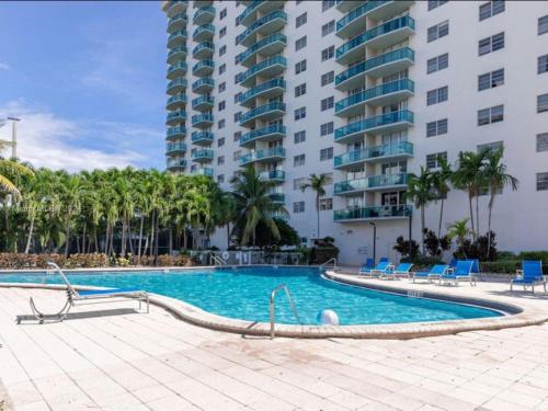 a swimming pool with chairs and a large building at Family Stay Ocean Reserve Resort Sunny Isles in Sunny Isles Beach
