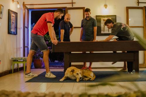a group of men standing around a table with a dog at Viajero Colonia Hostel in Colonia del Sacramento