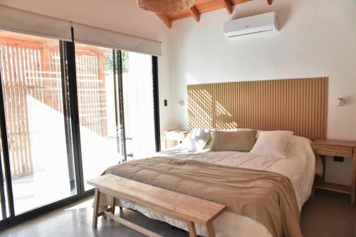 a bedroom with a large bed and a wooden bench at IZ chapa - Casa 1 - Casa en Chapa a estrenar a cuatro cuadras de Luna Roja - Hola Sur in Chapadmalal