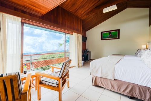 sypialnia z łóżkiem i dużym oknem w obiekcie Ficus Sunset Suites w mieście Monteverde