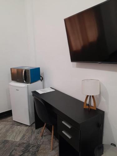 a black desk with a microwave and a television on a wall at Excelente apto Centro SP - Tudo a pé in Sao Paulo
