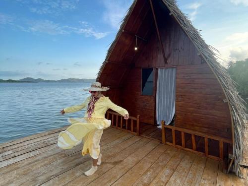 a woman is dancing on a dock in front of a cabin at Villa Mangrove Pulau Pahawang in Lampung