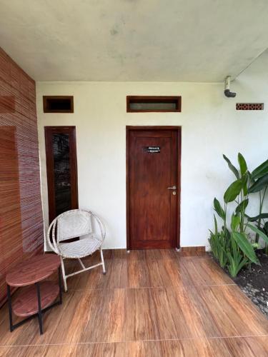 a room with a door and a chair and a wooden floor at The Inside House Medewi in Airsatang