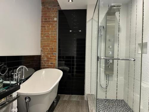 a bathroom with a tub and a glass shower at Lofts du Vieux-Port by Gray Collection in Montréal