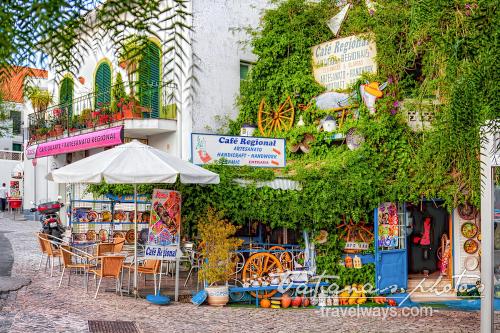 a cafe with chairs and an umbrella in front of a building at Charming house in Alte with pool in Alte