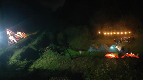 a group of people standing next to tents at night at D'Sentra Riverside Camp in Pengalengan