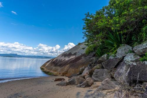 a beach with rocks and trees next to the water at Mansão VOAR in Florianópolis