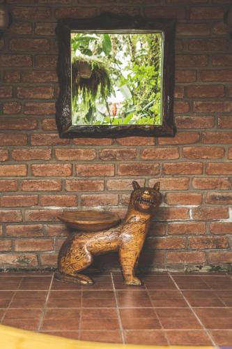 a statue of a cat sitting in front of a brick wall at Hostal Las Palmas in Puyo