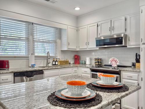 a kitchen with white cabinets and two bowls on a counter at The Caspian large family house with private pool in Summerville in Summerville