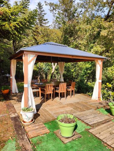 une terrasse en bois avec un kiosque, une table et des chaises dans l'établissement Val Paradis, à Espagnac-Sainte-Eulalie