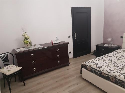 a bedroom with a dresser and a bed and a black door at K2 Montalcino Apartment in Torrenieri