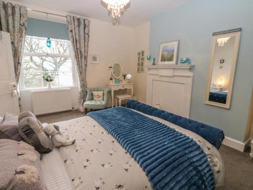a bedroom with a bed with a blue blanket on it at West Wing Cottage in Sandhoe