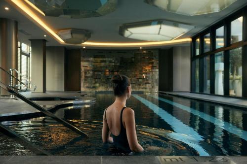 a woman sitting on the edge of a swimming pool at Excelsior Hotel Gallia, a Luxury Collection Hotel, Milan in Milan