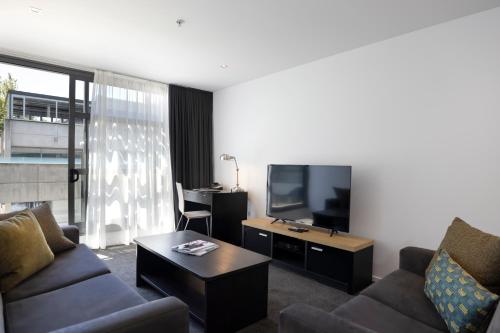 a living room with a couch and a tv at Quest Parnell Serviced Apartments in Auckland