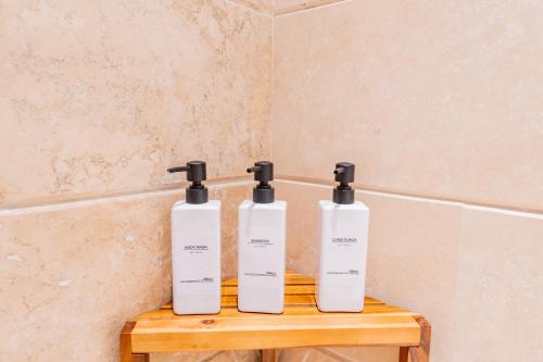three bottles on a wooden shelf in a bathroom at Condos Privados en Huatulco in Tangolunda