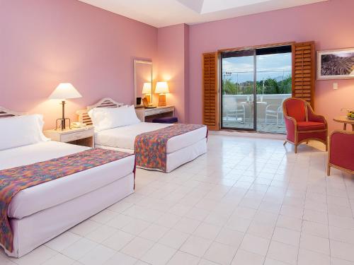 a hotel room with two beds and a balcony at Hotel Tocarema in Girardot