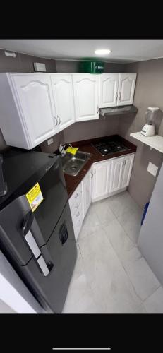 a kitchen with white cabinets and a black refrigerator at Excelente vista in Cartagena de Indias