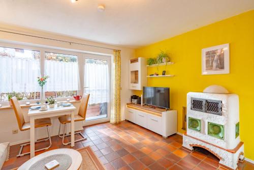 a yellow living room with a table and a tv at Ferienwohnungen Christoph in der Edelweißstraße in Pfaffing
