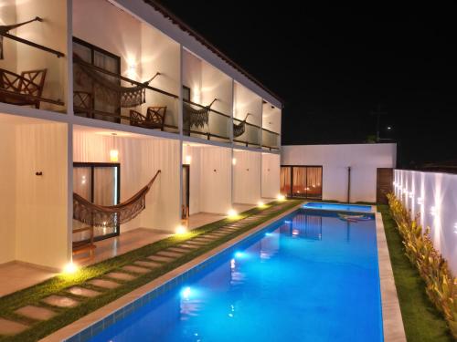 a swimming pool in front of a building at night at Yahweh Hotel in São Miguel do Gostoso