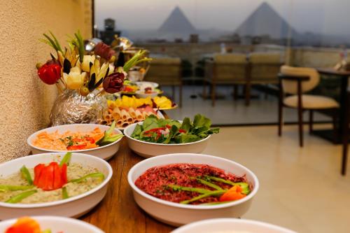a table topped with bowls of food and flowers at Rixoss Tower Pyramids View in Cairo