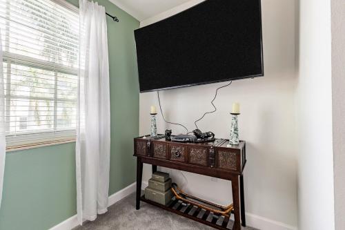 a room with a table with a television on a wall at Spacious 3BR 3BA with King Bed & Amazing Pools near Intercoastal, Lantana Beach, FL in Lantana