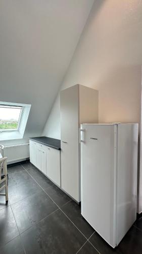  La cuisine est équipée de placards blancs et d'un réfrigérateur. dans l'établissement Appartement neuf 6 voyageurs, à Strasbourg